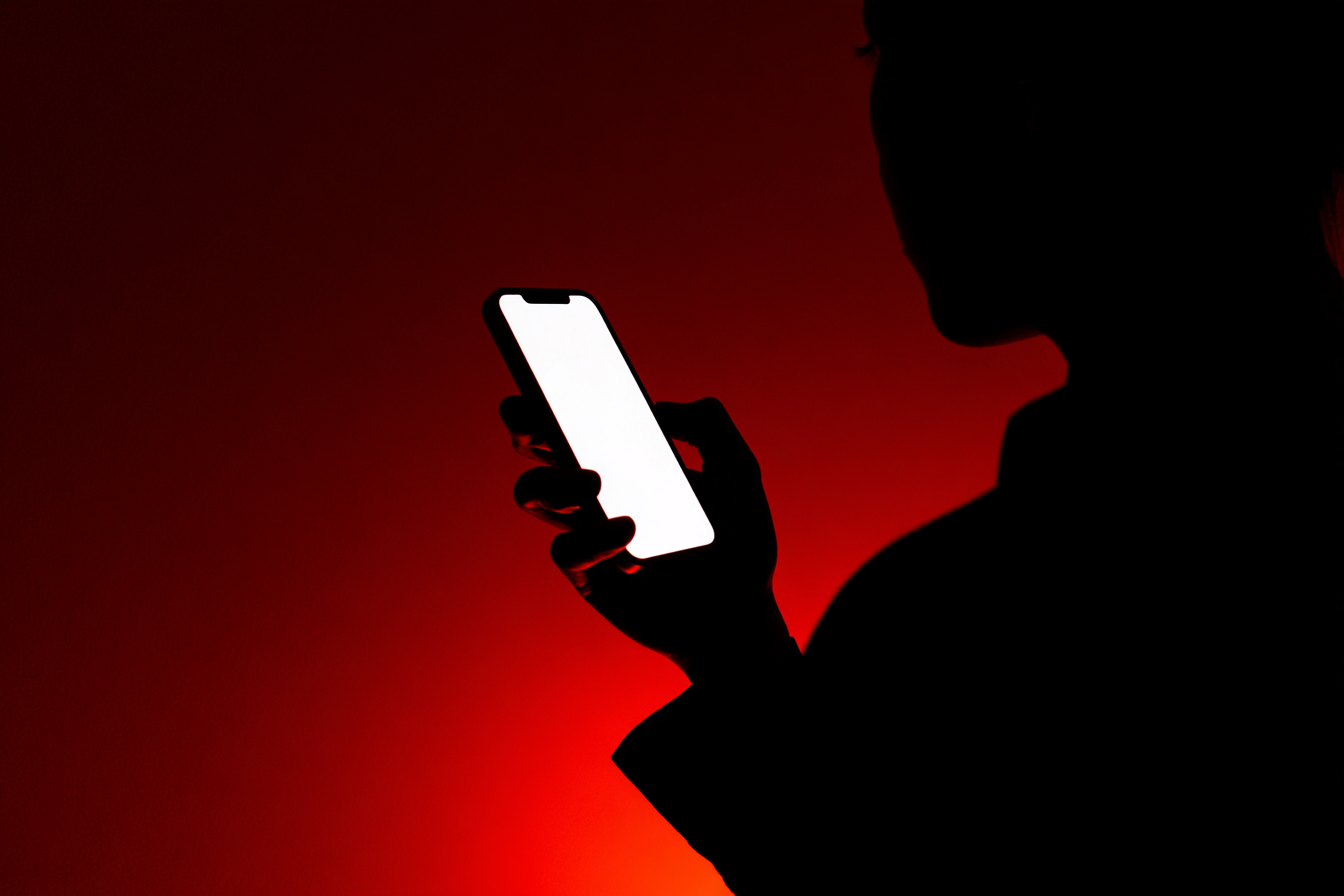Woman scrolling on phone in a dark room with dramatic red lighting